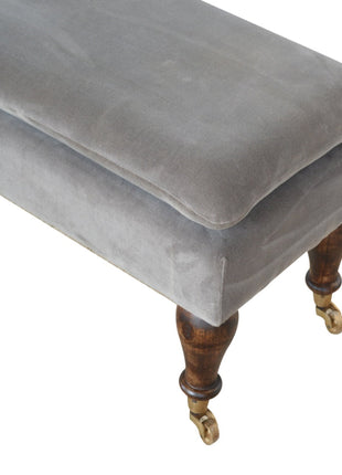 Banco de terciopelo gris con patas con ruedas