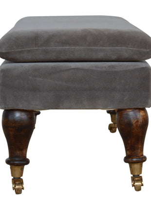 Banco de terciopelo gris con patas con ruedas